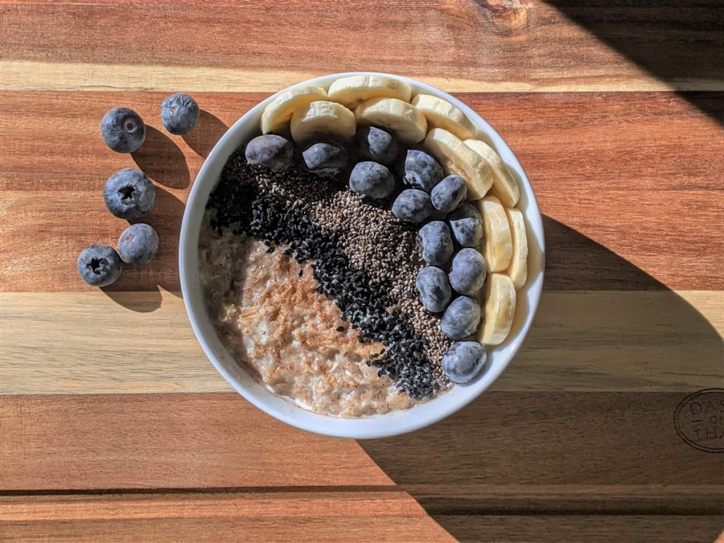 Kom havermout met blauwe bessen, banaan en chiazaad op een houten plank