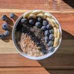 Kom havermout met blauwe bessen, banaan en chiazaad op een houten plank